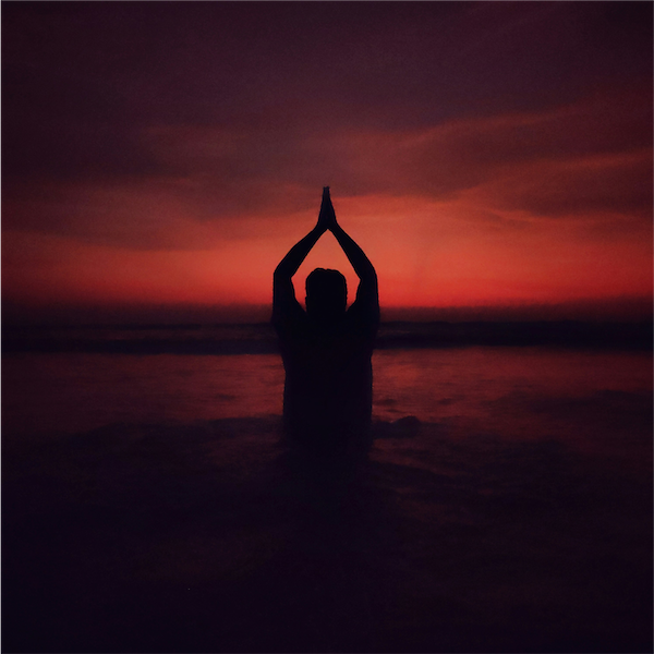a person meditating on the sunset